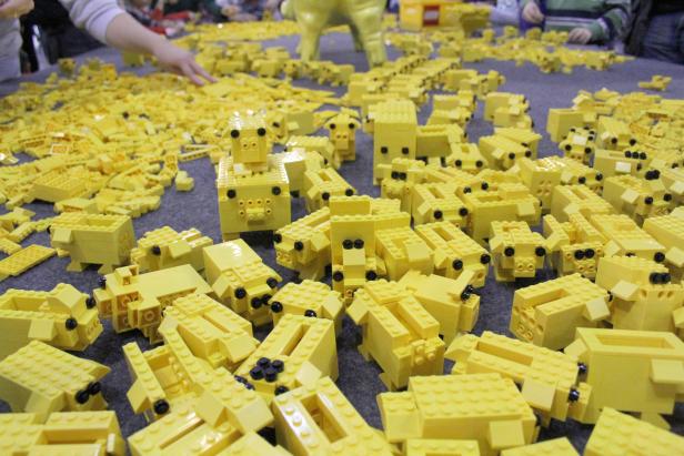 Viele gelbe Lego-Schweine liegen auf einem Tisch.