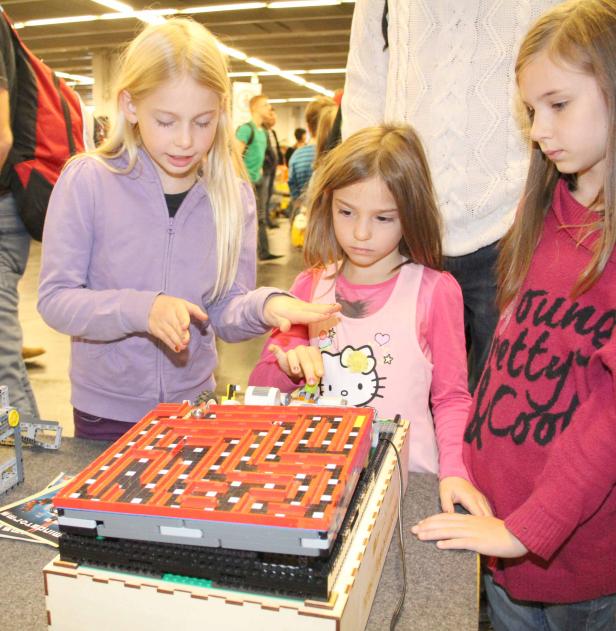 Drei Mädchen spielen mit einem Labyrinth aus Legosteinen.