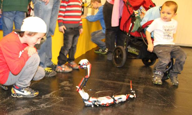 Kinder beobachten einen Roboter, der auf dem Boden steht.