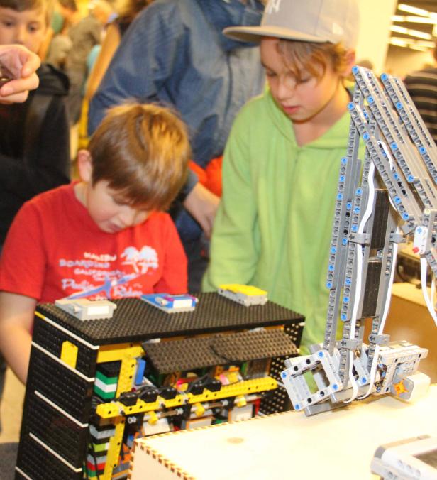 Zwei Kinder betrachten eine komplexe Konstruktion aus Legosteinen.