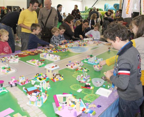 Kinder bauen gemeinsam an einem großen Tisch mit Legosteinen.