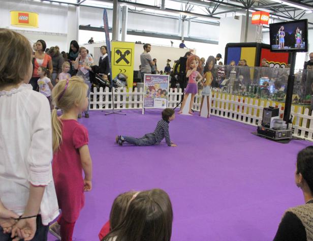 Ein Kind krabbelt auf einer lila Fläche bei einer Lego-Veranstaltung.