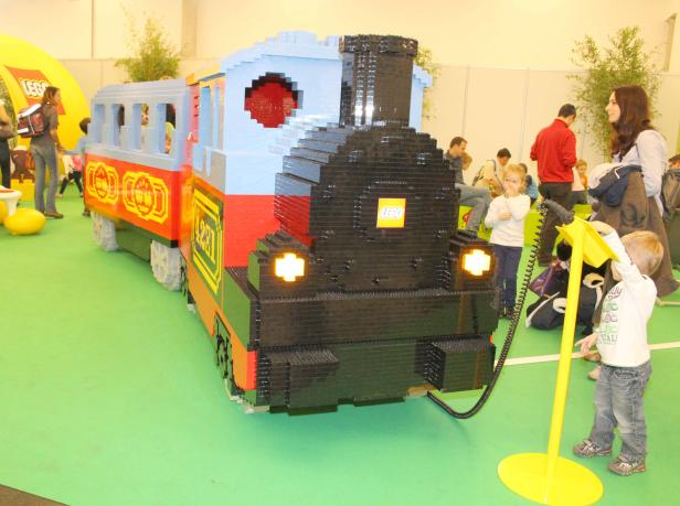 Ein großer Zug aus Legosteinen steht auf einer grünen Fläche.