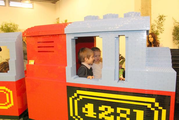Zwei Kinder schauen aus dem Fenster eines Zuges, der aus Legosteinen gebaut wurde.