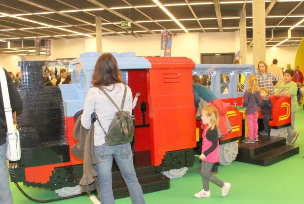Besucher, darunter Kinder, erkunden eine große Modelleisenbahn aus Legosteinen.