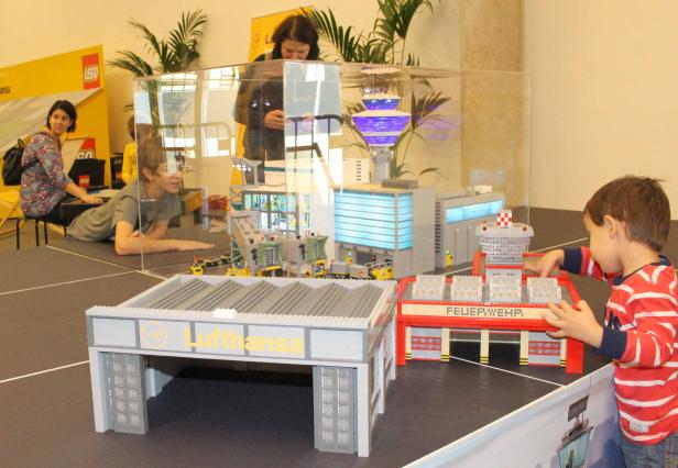 Ein Junge spielt mit einem LEGO-Modell eines Flughafens mit Lufthansa-Hangar und Feuerwache.