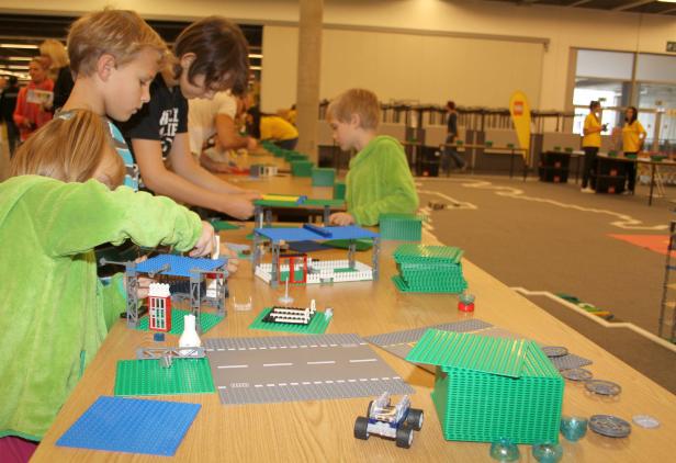 Kinder bauen mit Legosteinen an einem Tisch.