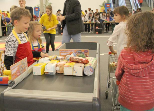 Kinder stehen an einer Supermarktkasse mit Lebensmitteln auf dem Band.