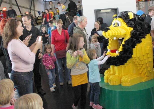 Kinder betrachten eine große Löwenstatue aus Legosteinen.