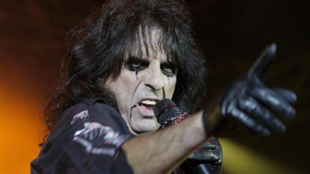 Alice Cooper tritt in schwarzer Kleidung und mit dunklem Make-up auf.