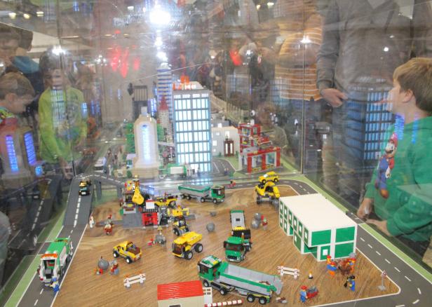 Eine Lego-Stadt mit Baustelle und mehreren Kindern, die das Diorama betrachten.