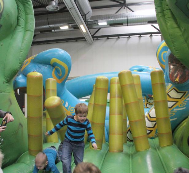 Kinder spielen auf einer Hüpfburg mit Hindernissen.