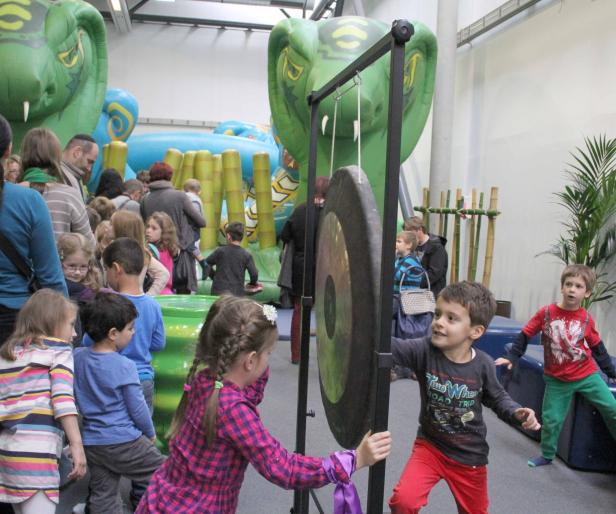 Kinder spielen mit einem Gong vor einer aufblasbaren Kobra.