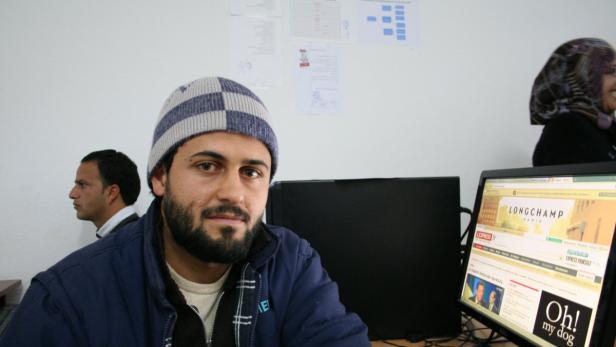 Ein Mann mit Mütze sitzt vor einem Computer, auf dem die Webseite von Longchamp zu sehen ist.