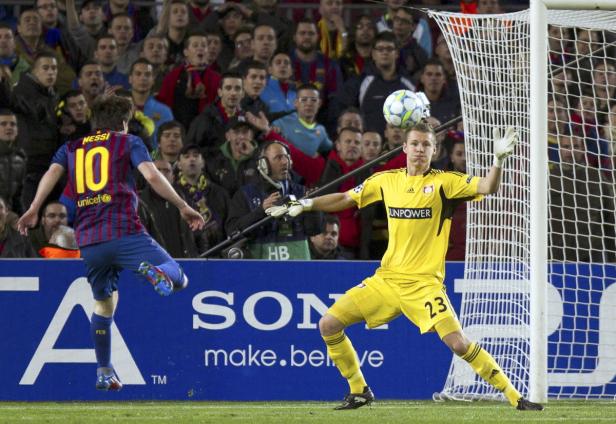 Lionel Messi schießt den Ball, während der Torwart ihn abwehrt.