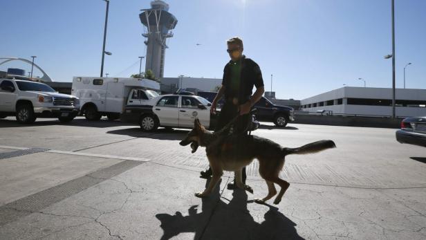 Ein Polizist führt einen Hund am Los Angeles International Airport aus.
