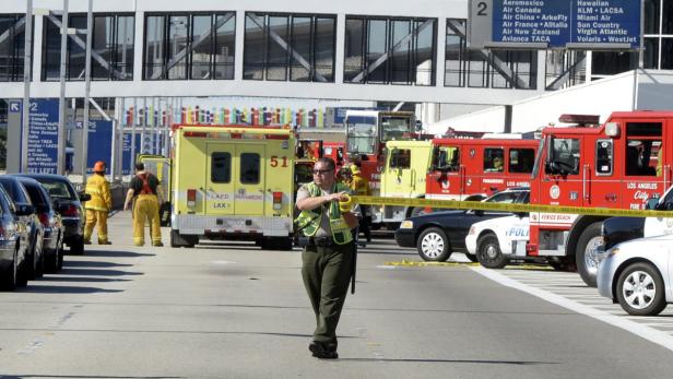 Ein Mann in Uniform sichert eine Szene mit Feuerwehr- und Rettungsfahrzeugen am Flughafen Los Angeles.