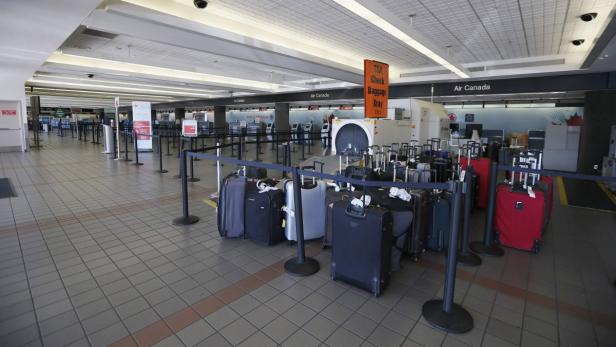 Eine Gepäckkontrollstelle von Air Canada mit mehreren Koffern vor einem Röntgengerät.