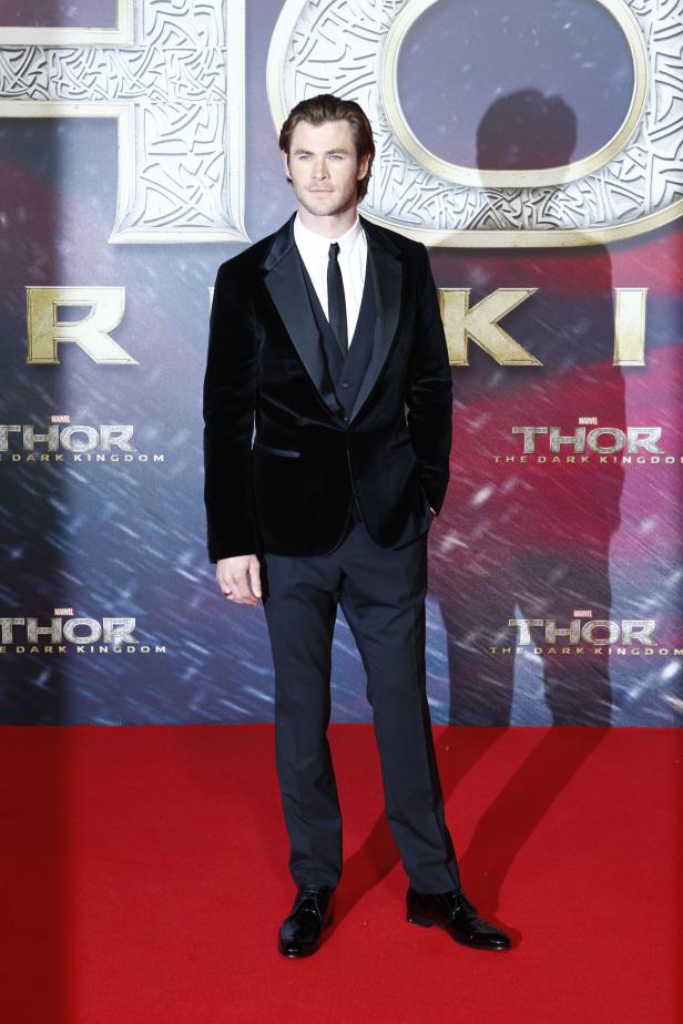 Chris Hemsworth posiert vor einem „Thor: The Dark Kingdom“-Poster.