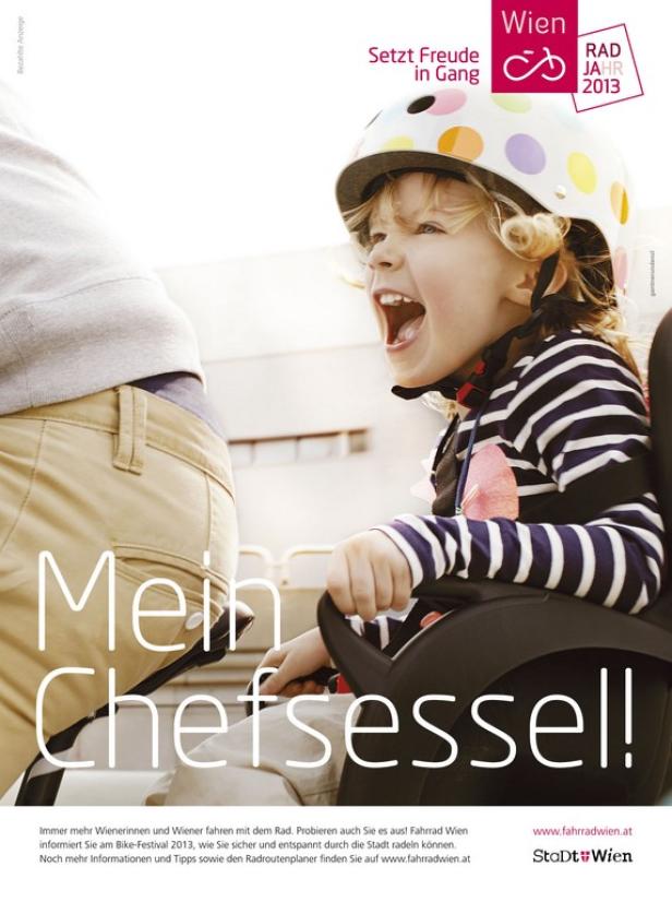 Ein aufgeregtes Kind mit Fahrradhelm sitzt in einem Fahrradsitz.