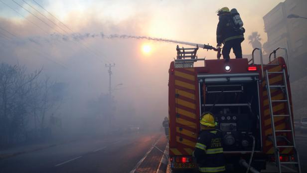 Feuerwehrleute bekämpfen einen Brand mit einem Wasserwerfer von einem Feuerwehrauto aus.