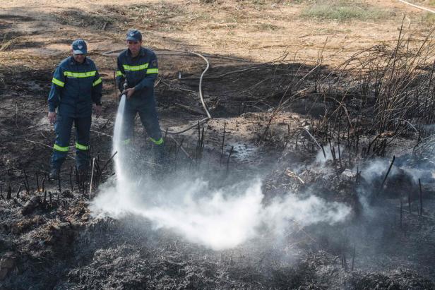 Zwei Feuerwehrleute löschen einen Brand mit einem Wasserstrahl.