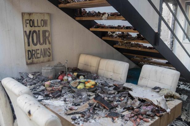 Ein durch ein Feuer zerstörtes Wohnzimmer mit einer Tafel, auf der „Follow Your Dreams“ steht.