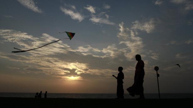 Eine Mutter und ihr Kind lassen bei Sonnenuntergang einen Drachen steigen.