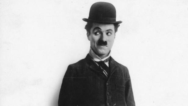 Charlie Chaplin mit Melone und aufgemalten Schnurrbart blickt zur Seite.