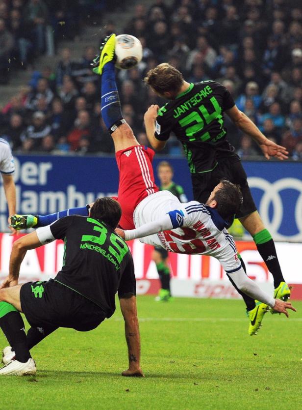 Martin Stranzl (Nr. 39) gewann mit Gladbach in Hamburg Ein Fußballspieler führt einen Fallrückzieher aus, während andere Spieler zusehen.