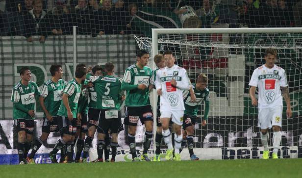 Fußballspieler von zwei Mannschaften stehen auf dem Spielfeld.