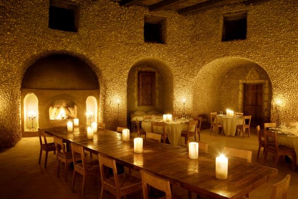 Ein Speisesaal mit Steingewölbe ist mit Kerzen beleuchtet.