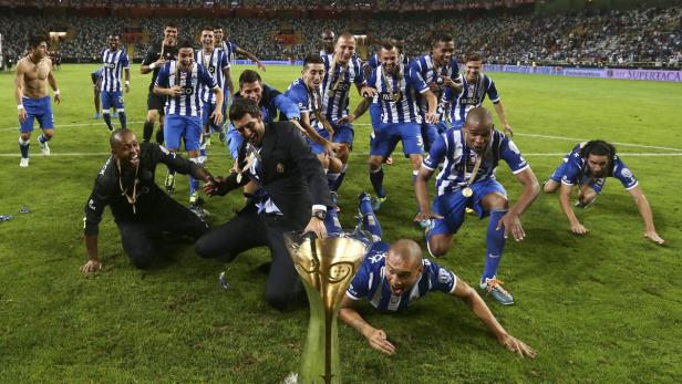 Fußballspieler feiern mit dem Pokal auf dem Rasen.