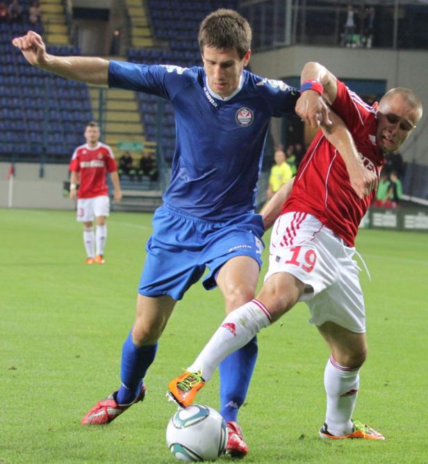 Zwei Fußballspieler kämpfen um den Ball auf dem Spielfeld.