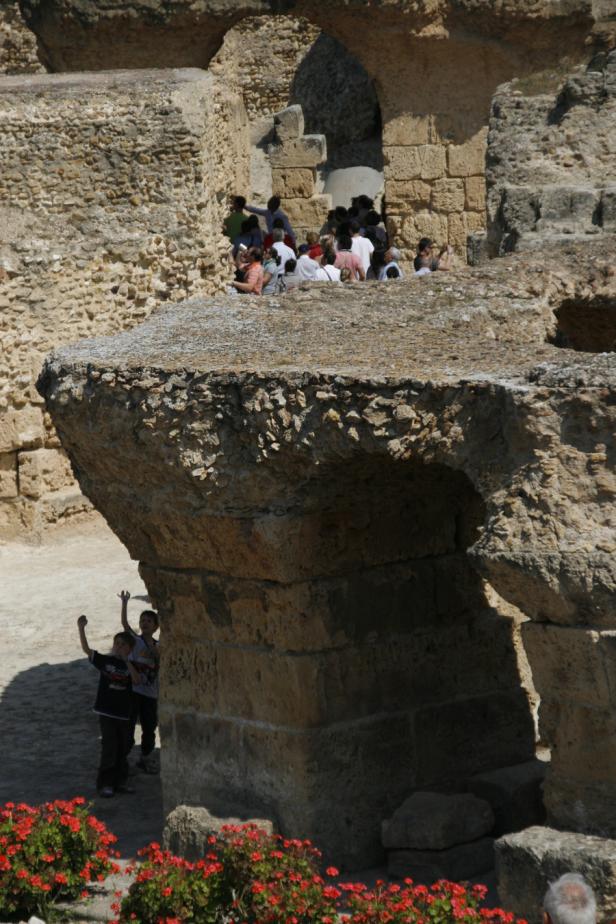 Kinder erkunden die Ruinen eines alten römischen Amphitheaters.