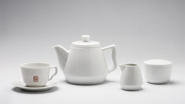 Ein Teeservice aus weißem Porzellan, bestehend aus Kanne, Tasse, Milchkännchen und Zuckerdose.