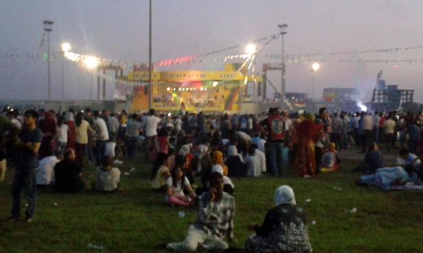 Eine Menschenmenge versammelt sich vor einer Bühne im Freien.