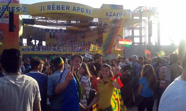 Eine Menschenmenge feiert Newroz mit kurdischen Flaggen und Bannern.