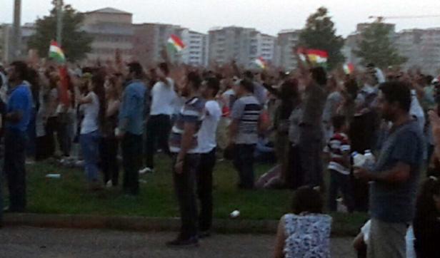 Eine Menschenmenge demonstriert mit kurdischen Flaggen in einer städtischen Umgebung.