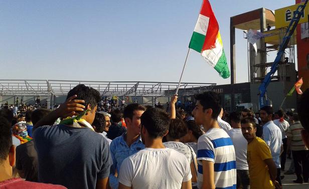 Eine Menschenmenge mit der kurdischen Flagge bei einer Veranstaltung.