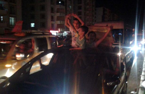 Drei Kinder stehen auf dem Dach eines Autos und jubeln in der Nacht.