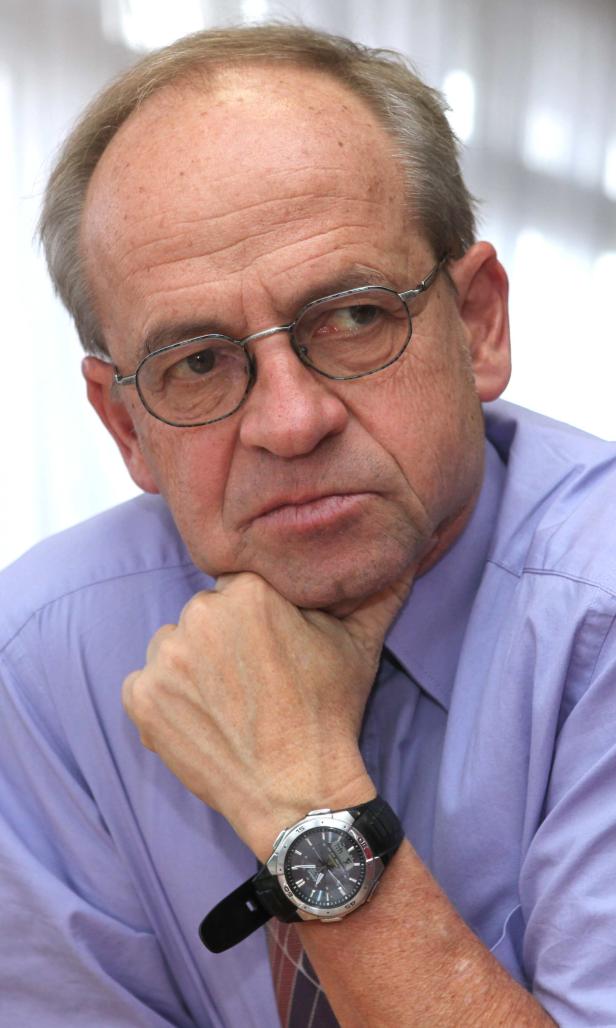 Ein Mann mit Brille stützt sein Kinn auf seine Hand.