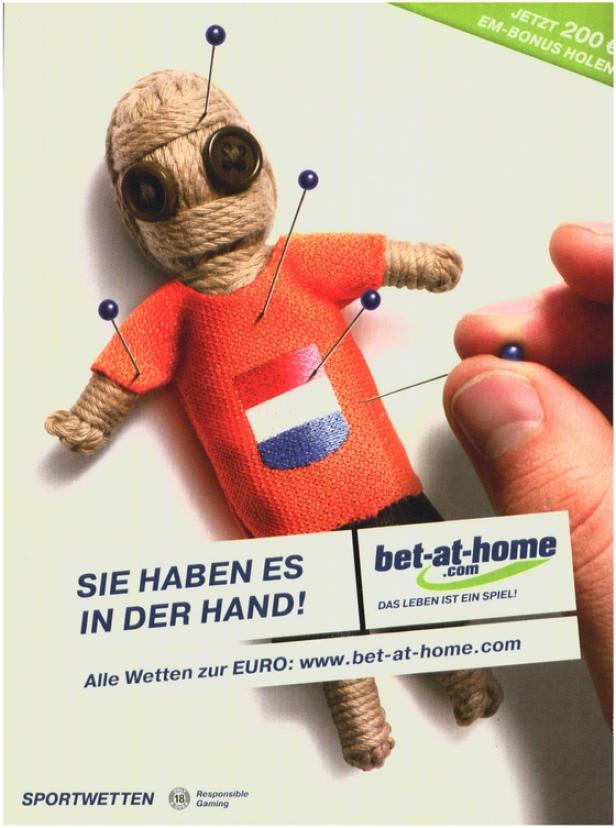 sportnet.at-iPhone-App Eine Voodoo-Puppe mit Nadeln, die ein Trikot mit der Flagge der Niederlande trägt, bewirbt „bet-at-home“.