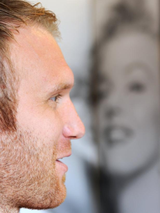 Ein Mann mit Bart im Profil, im Hintergrund ein verschwommenes Porträt von Marilyn Monroe.