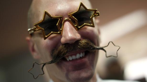 Ein Mann mit Sternenbrille und einem Bart, der in Sternformen endet, lächelt.