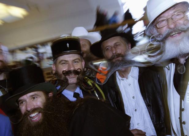 Mehrere Männer mit aufwendigen Bärten und Hüten lächeln in die Kamera.