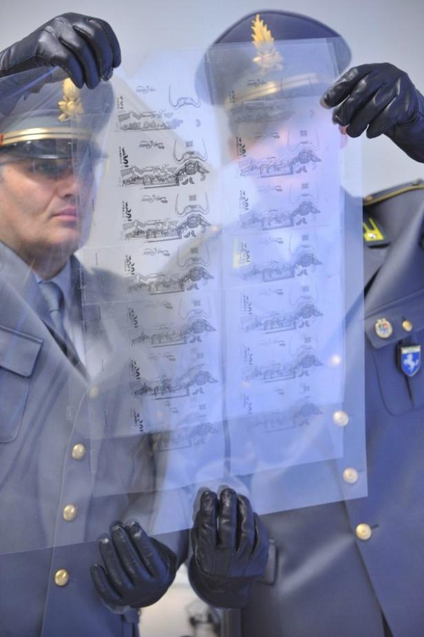 Zwei Männer in Uniform betrachten einen Bogen mit Banknotenentwürfen.