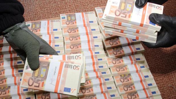 Zwei Hände mit Handschuhen halten Bündel von 50-Euro-Scheinen.