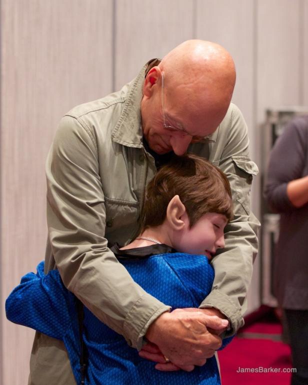 Patrick Stewart umarmt einen jungen Fan, der als Spock verkleidet ist.