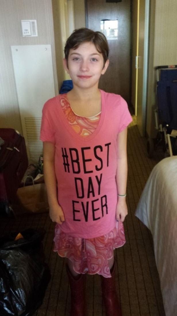 Ein junges Mädchen trägt ein rosa T-Shirt mit der Aufschrift „#BEST DAY EVER“.